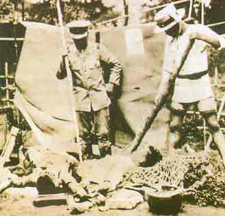A photograph from the 1923 Kantō Massacre showing two Japanese men standing beside a victim's body. (Wikimedia Commons / Public Domain)
